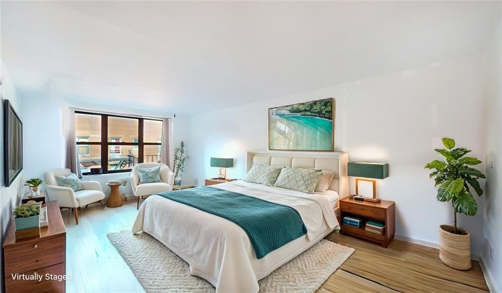 a bedroom with a large bed a large window and potted plant on the dresser