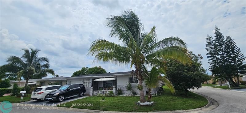 a front view of a house with garden and trees