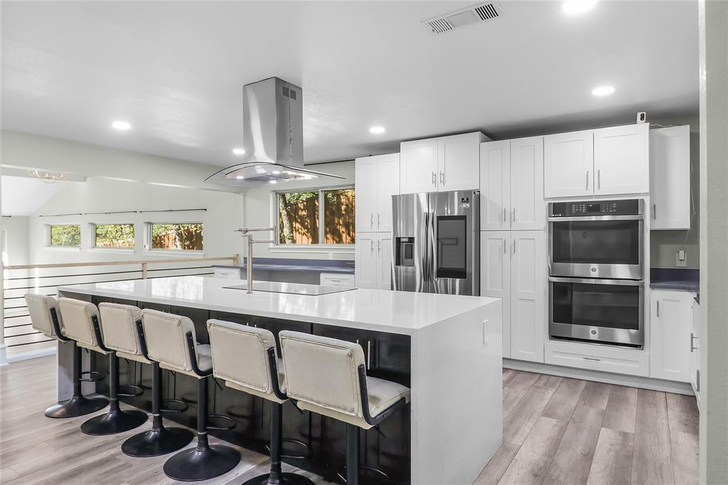 a kitchen with stainless steel appliances a dining table chairs and microwave