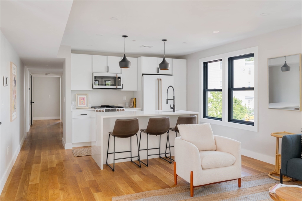 a living room with stainless steel appliances kitchen island granite countertop furniture and a wooden floor