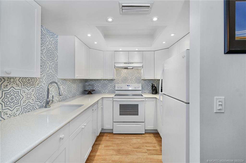 a kitchen with a sink a white cabinets and stainless steel appliances