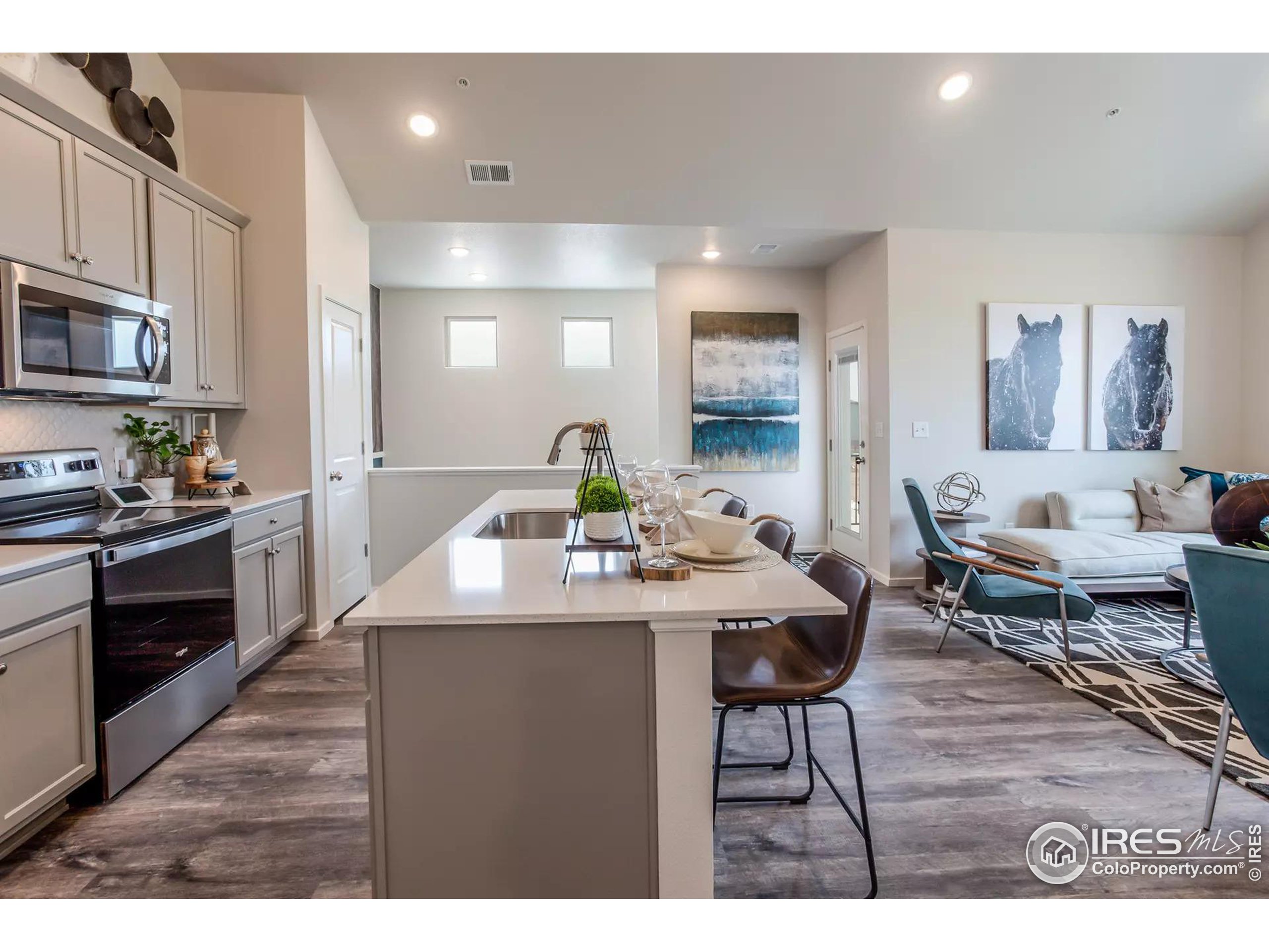 a living room with stainless steel appliances kitchen island granite countertop furniture a rug kitchen view and a chandelier