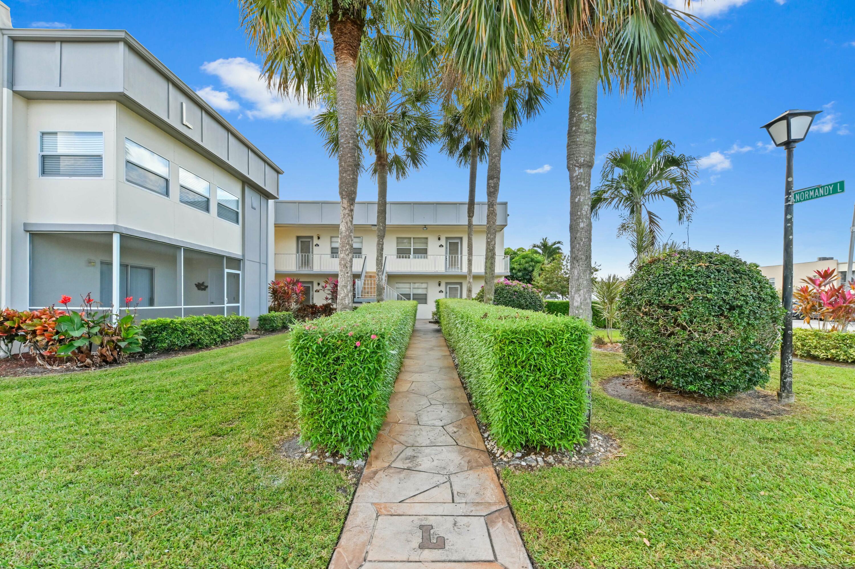 a view of a pathway with a big yard plants and palm trees