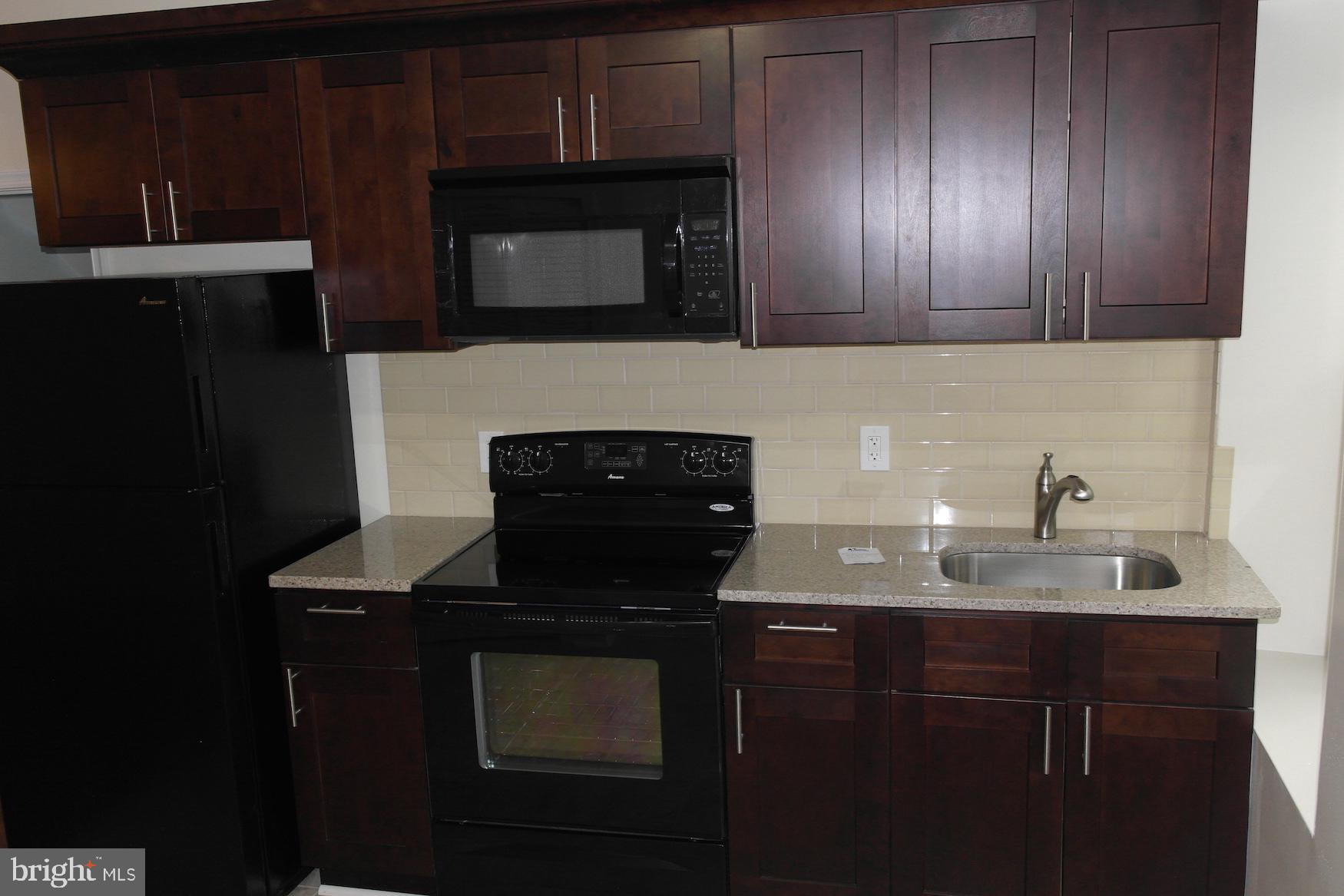 a kitchen with granite countertop wood cabinets stainless steel appliances and a sink