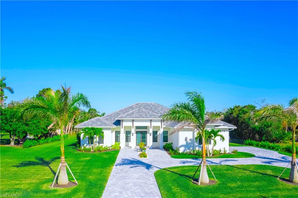 a front view of a house with a yard and palm trees