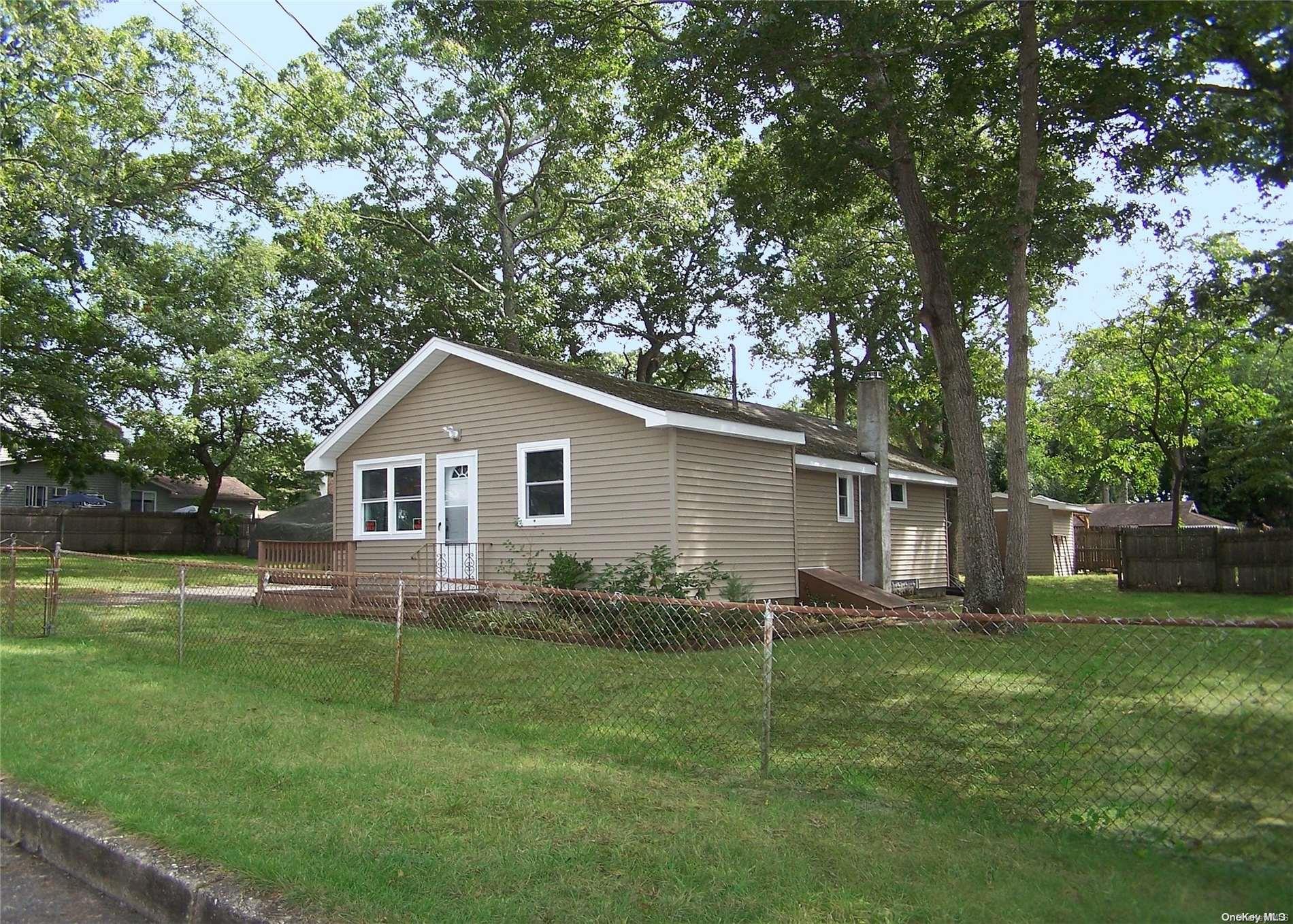 a backyard of a house with lawn chairs plants and tree