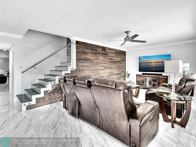 a living room with furniture a flat screen tv and kitchen view