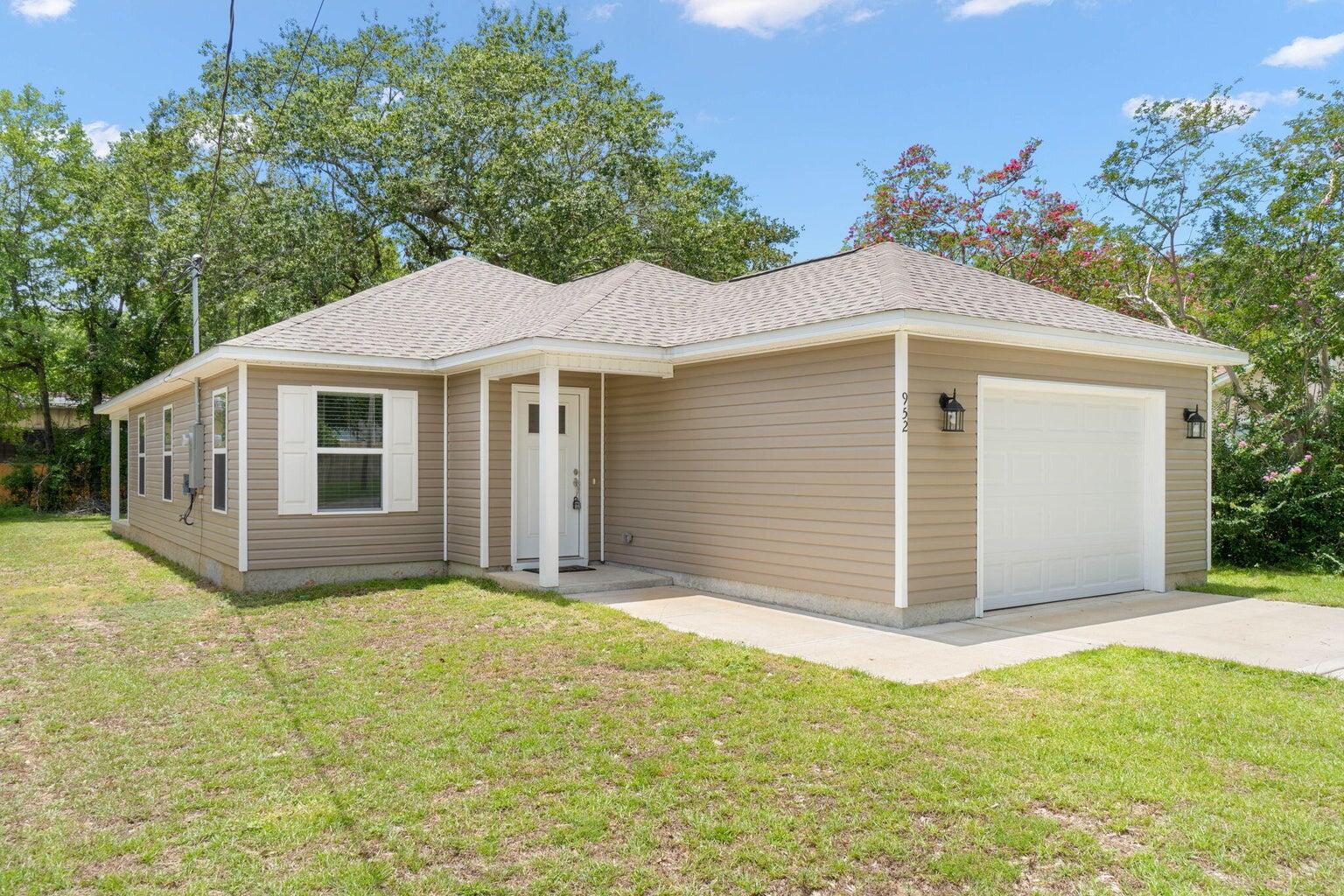 a front view of house with yard and trees in the background