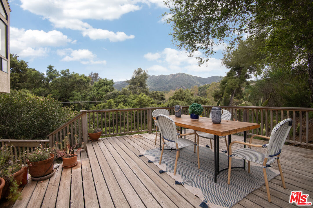 a view of a roof deck with table and chairs a barbeque with wooden floor and fence