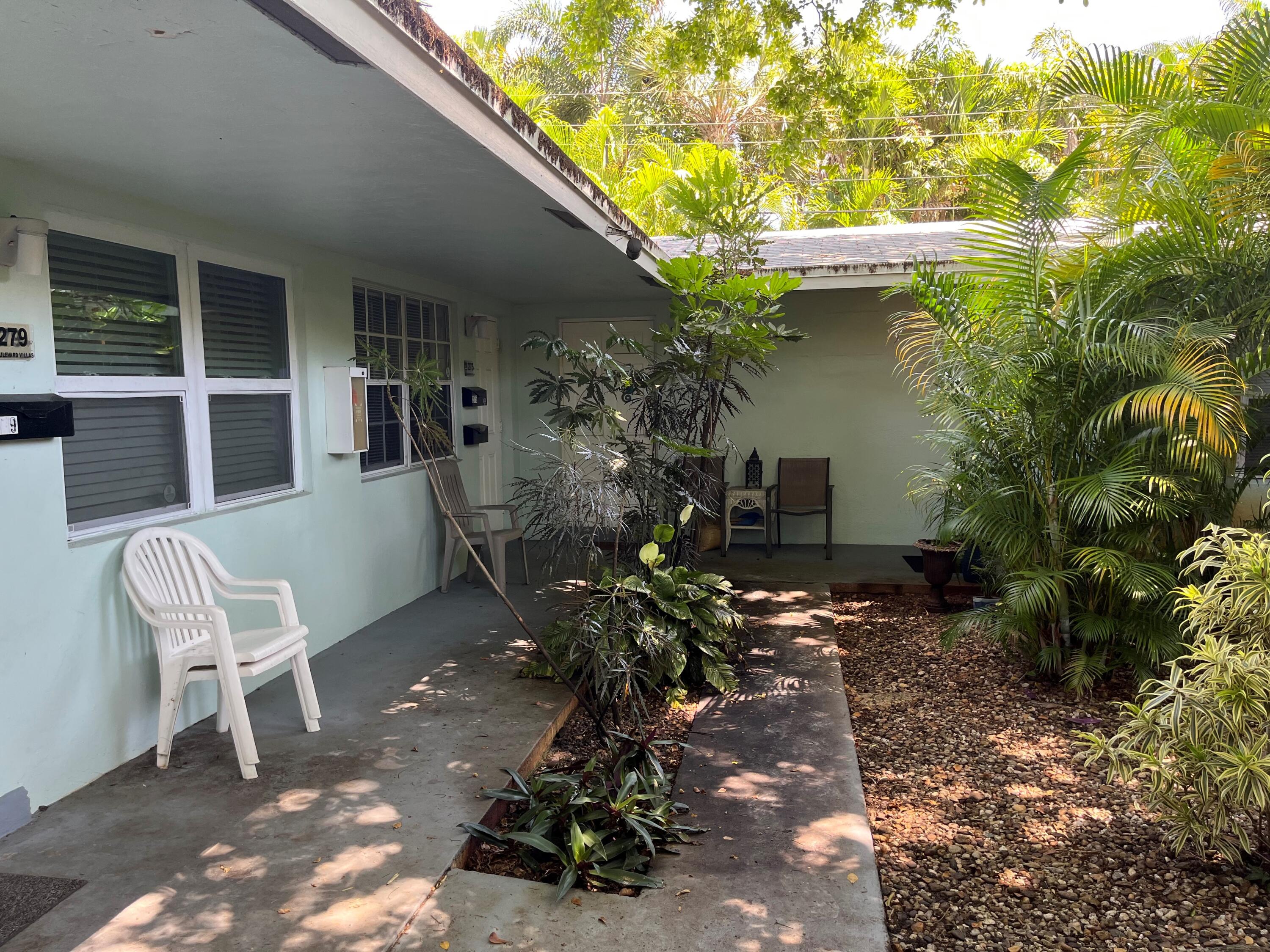 a backyard of a house with table and chairs potted plants with wooden fence