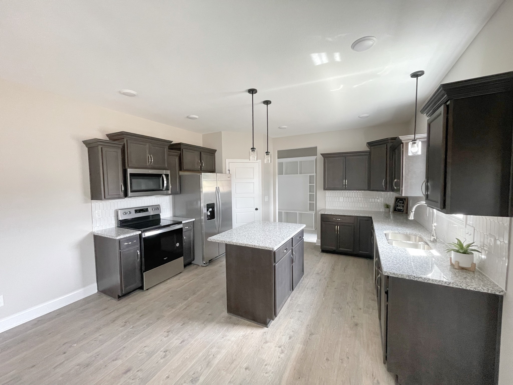 a large kitchen with kitchen island a counter top space stainless steel appliances and cabinets