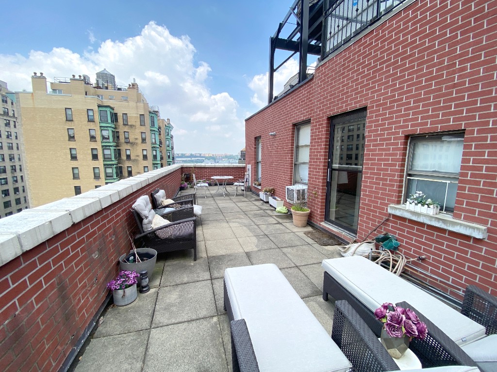 a roof deck with couches and potted plants