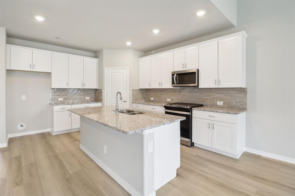 a kitchen with granite countertop white cabinets stove top oven and sink