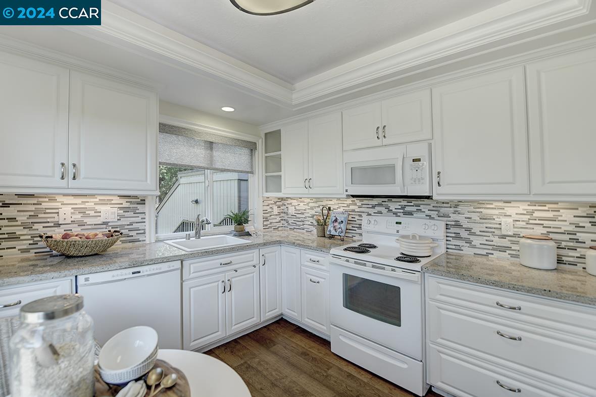 a kitchen with granite countertop white cabinets and white appliances