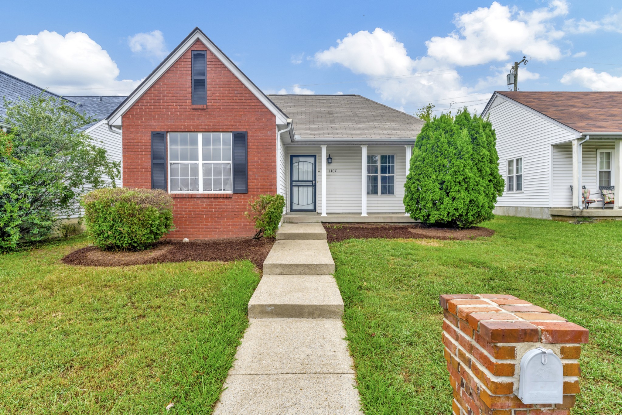 a front view of a house with a yard and potted plants