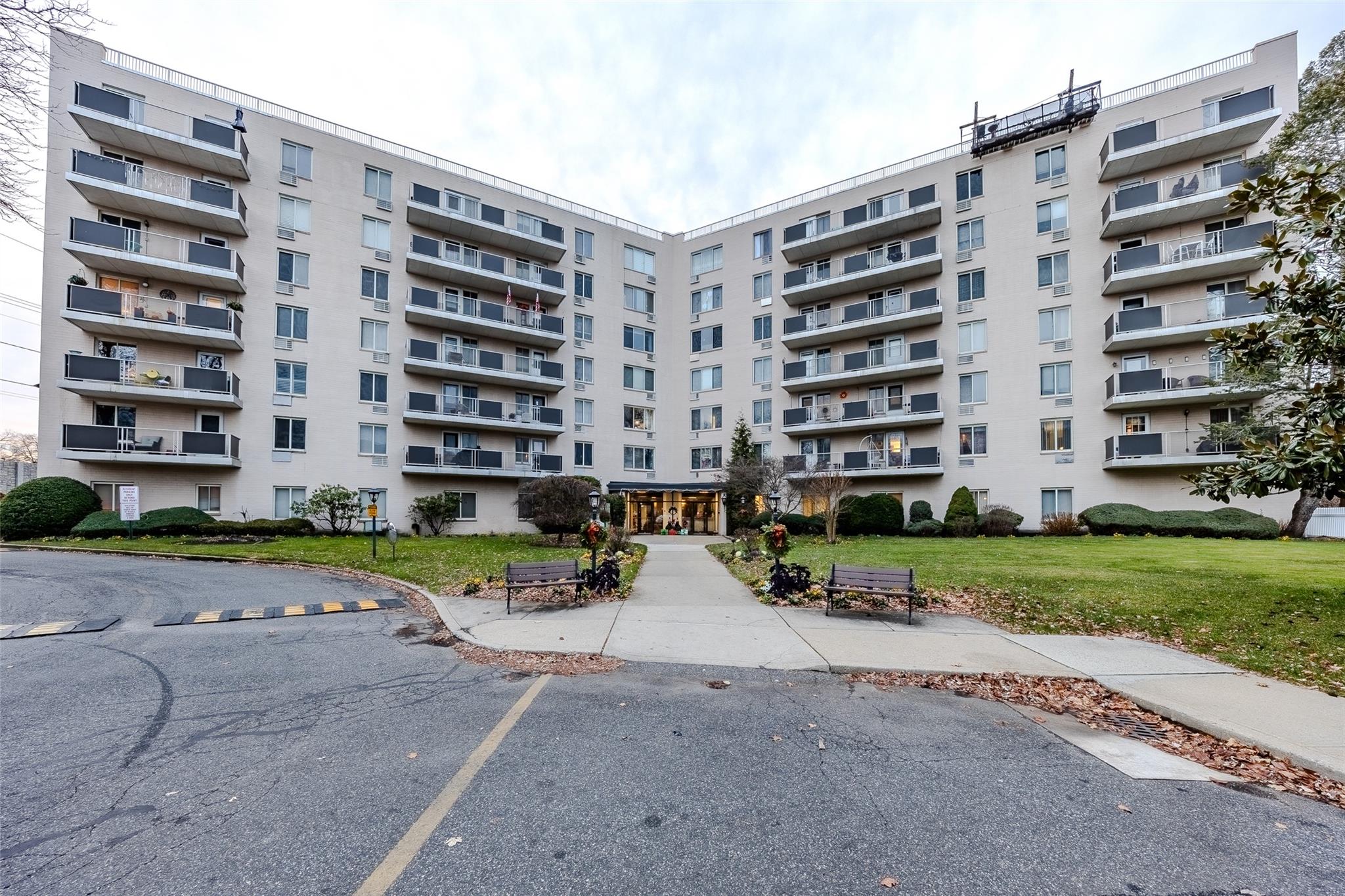 a front view of a building with a yard and parking space