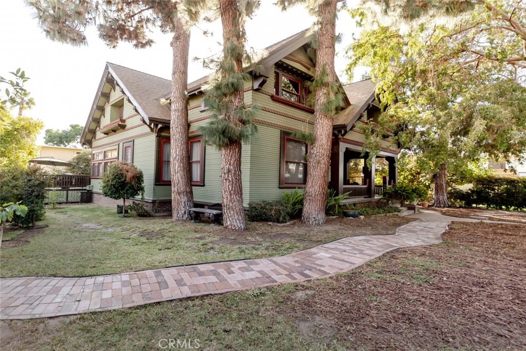 a view of a white house next to a yard with big trees