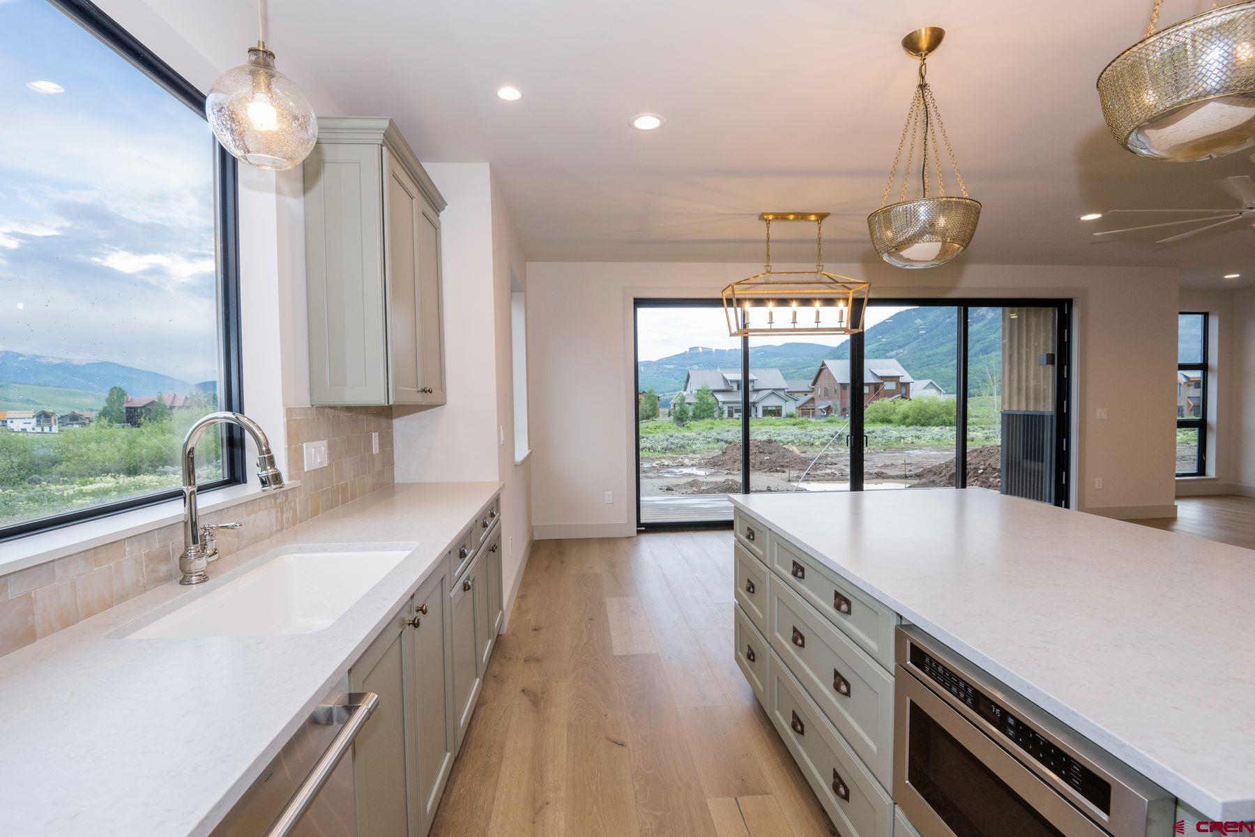 a large kitchen with kitchen island a large counter space a large window and stainless steel appliances