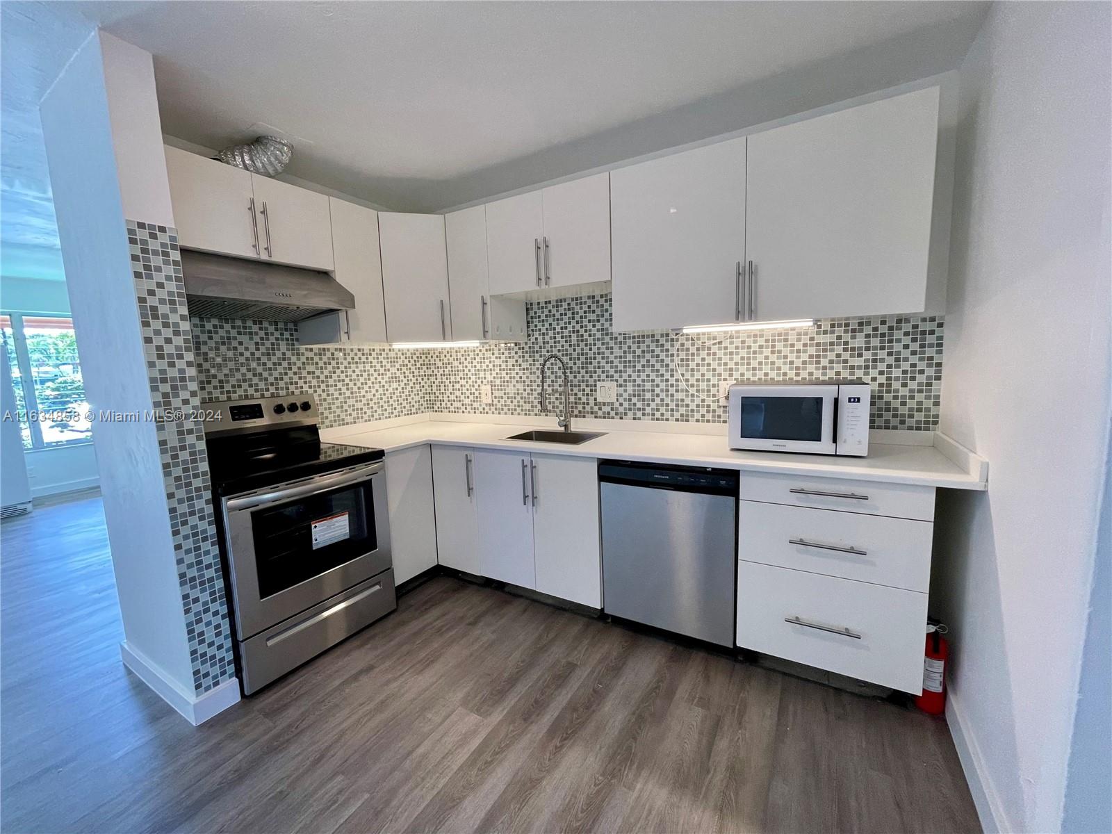 a kitchen with granite countertop white cabinets and stainless steel appliances