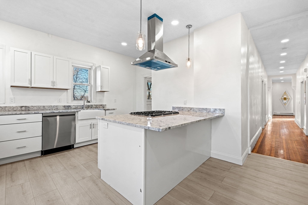 a kitchen with a sink a stove cabinets and wooden floor