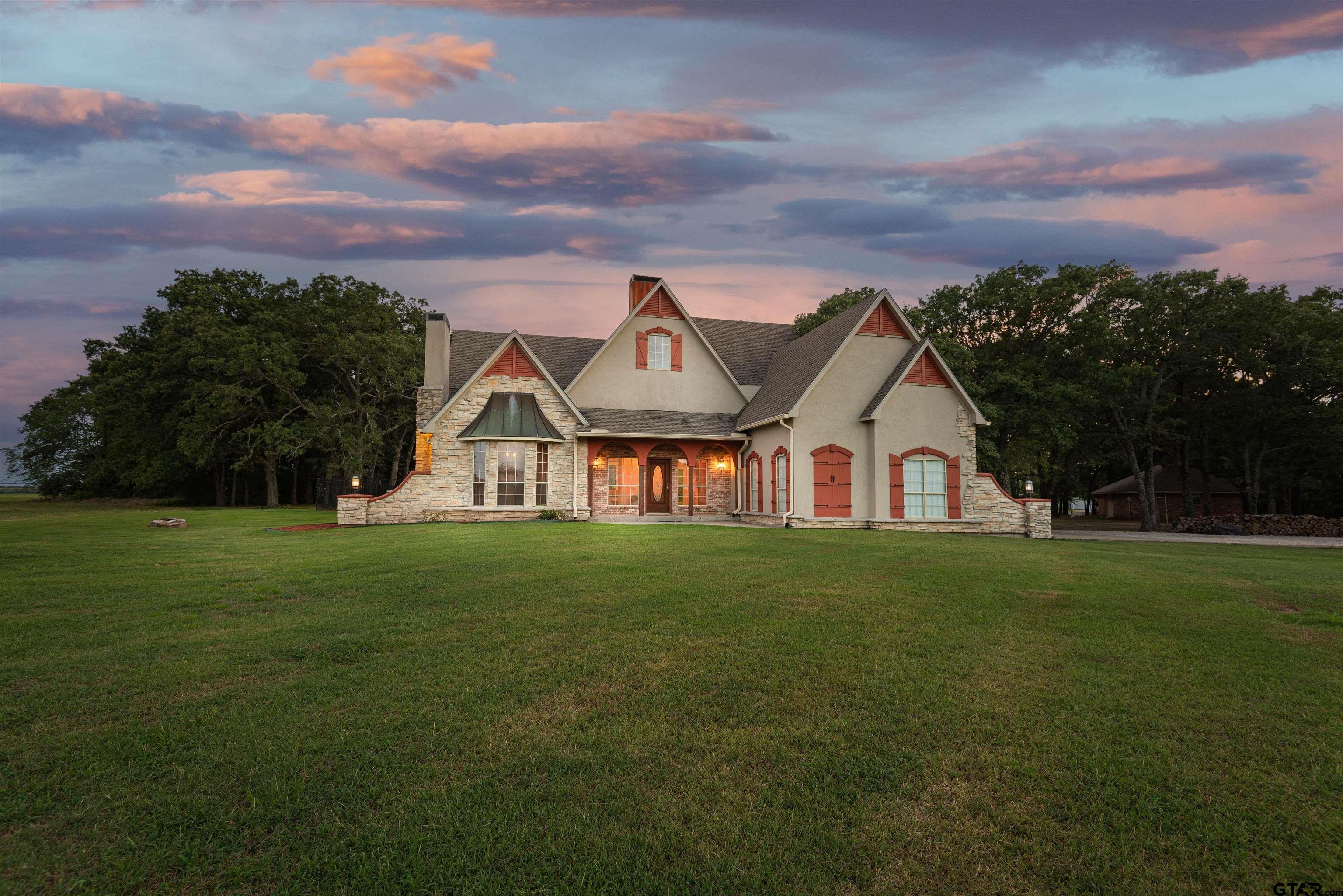 a view of a big house with a big yard and large trees