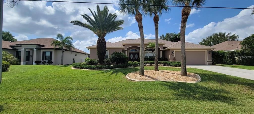 a view of a house with a yard and palm tree