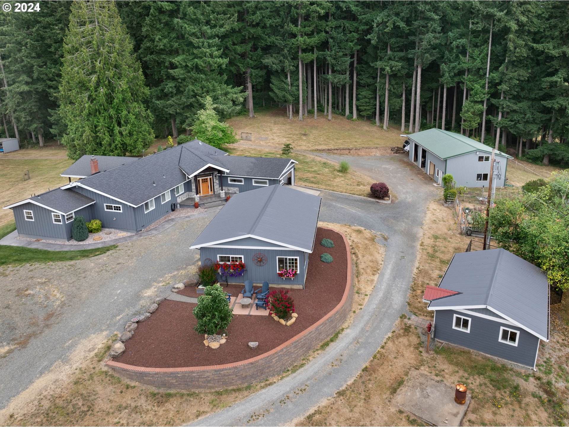 an aerial view of a house with yard and trees in the background