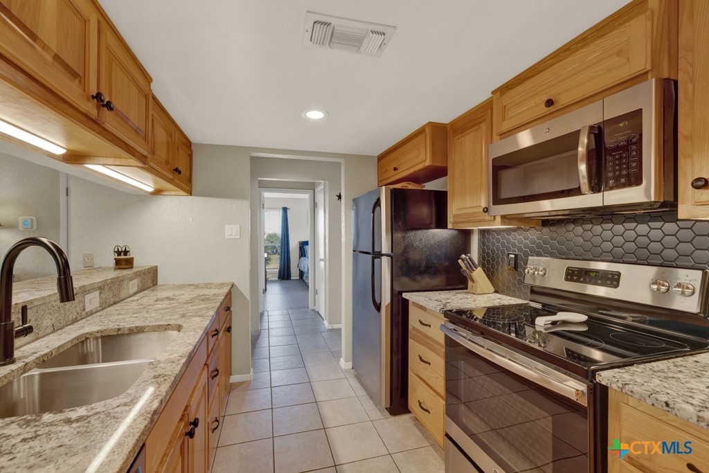 a kitchen with stainless steel appliances granite countertop a sink stove and refrigerator