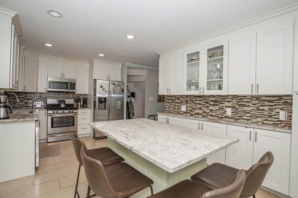 a kitchen with kitchen island a refrigerator stove microwave and cabinets