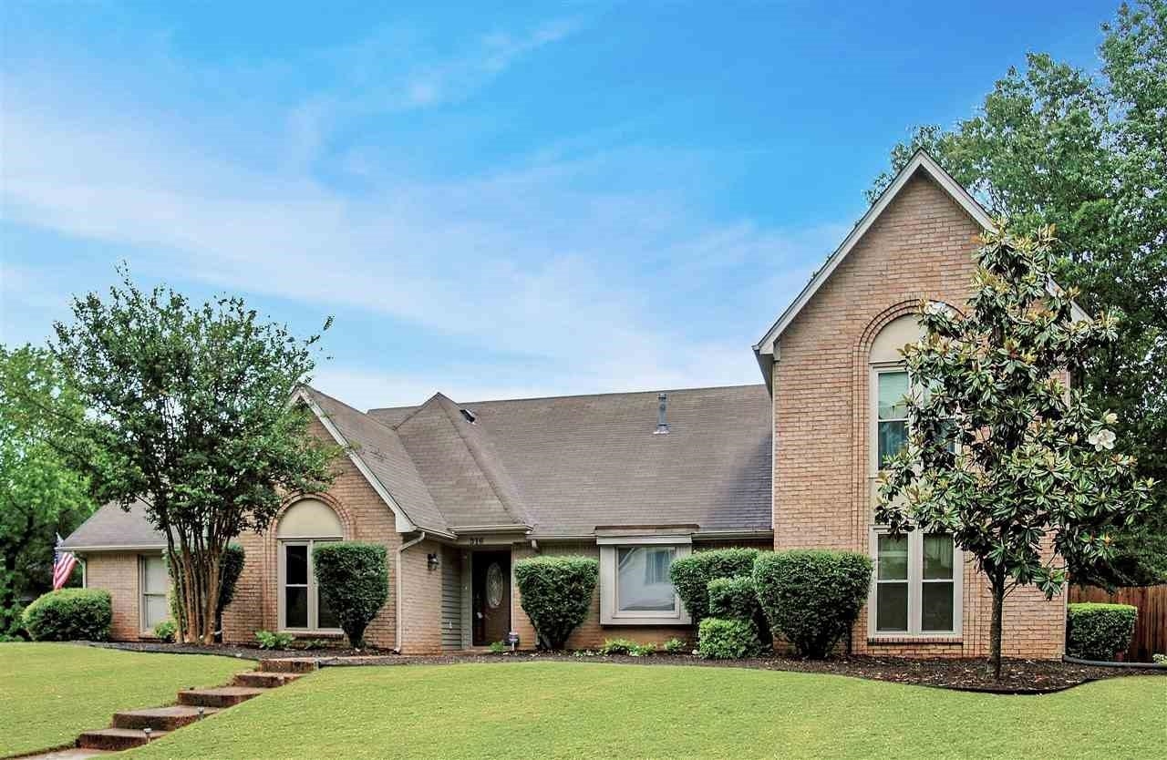 a front view of a house with a garden and trees