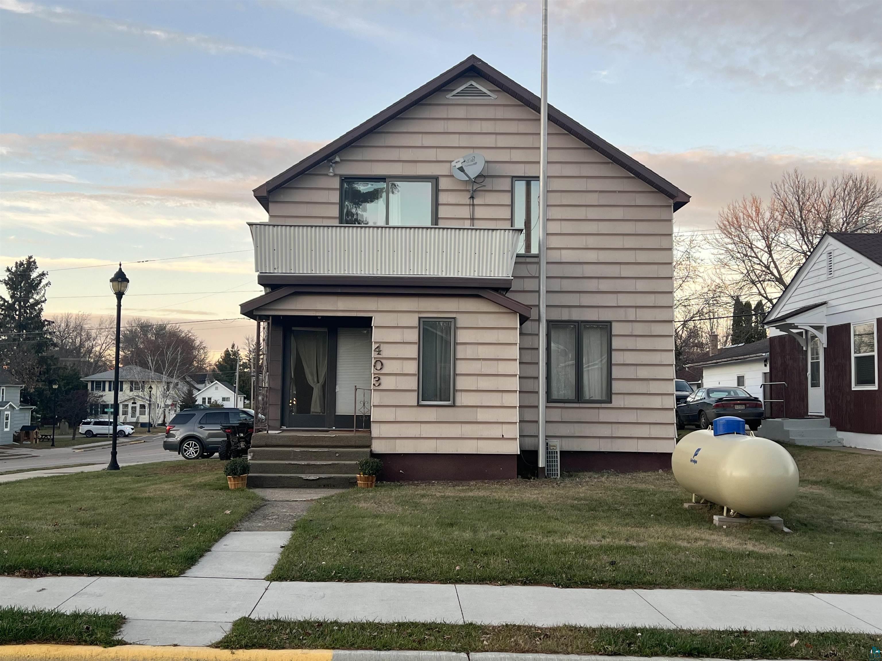 View of front of home with a lawn and a balcony