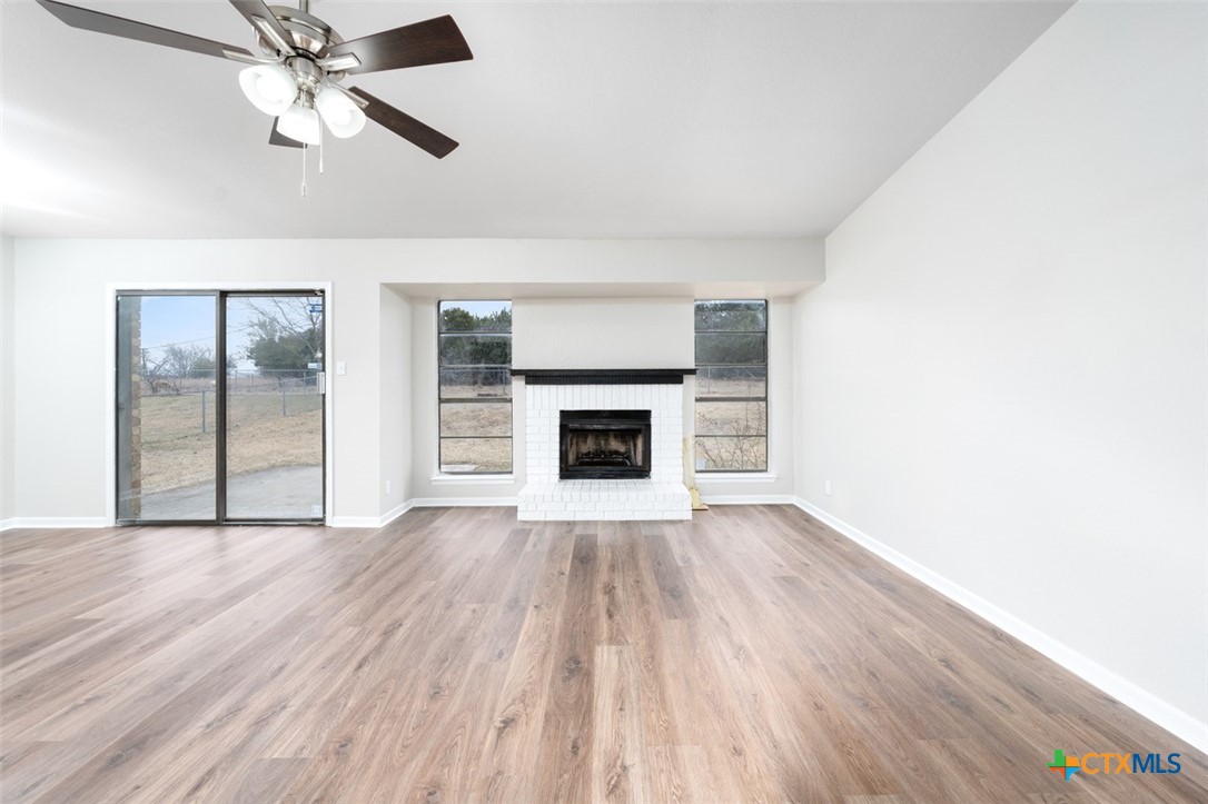 an empty room with wooden floor a ceiling fan and fireplace