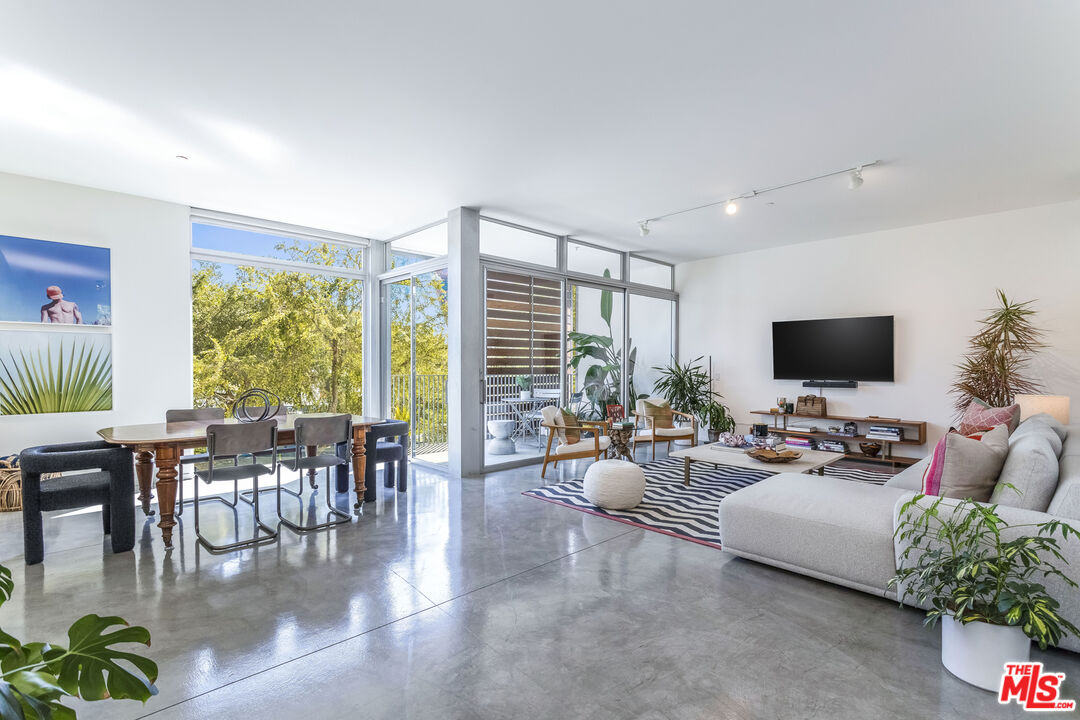 a living room with furniture floor to ceiling window and a flat screen tv