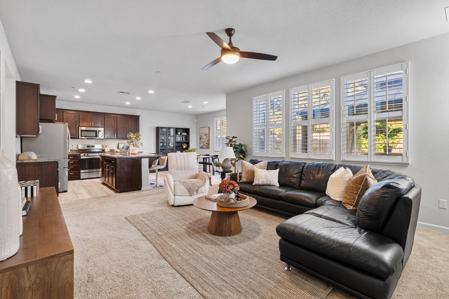 a living room with stainless steel appliances furniture a rug kitchen view and a window