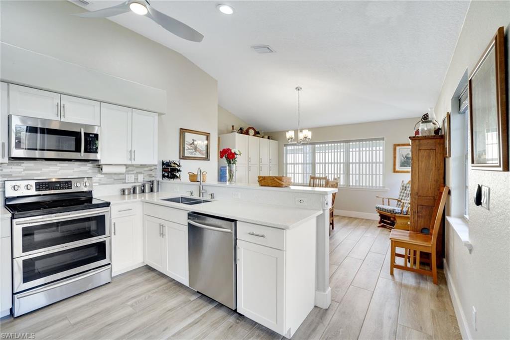 Kitchen featuring white cabinets, lofted ceiling, kitchen peninsula, and appliances with stainless steel finishes