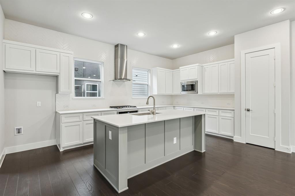 a kitchen with a sink stove a refrigerator and white cabinets with wooden floor