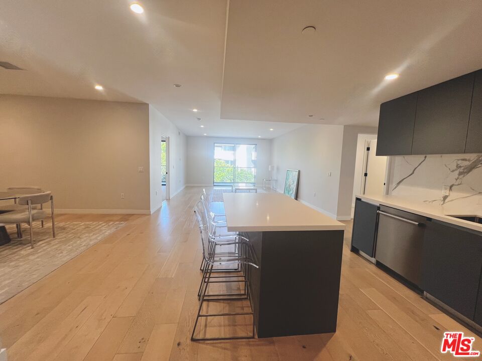 a kitchen with stainless steel appliances a kitchen island hardwood floor sink stove and granite counter top