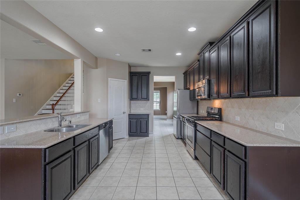 a large kitchen with stainless steel appliances a sink stove and cabinets