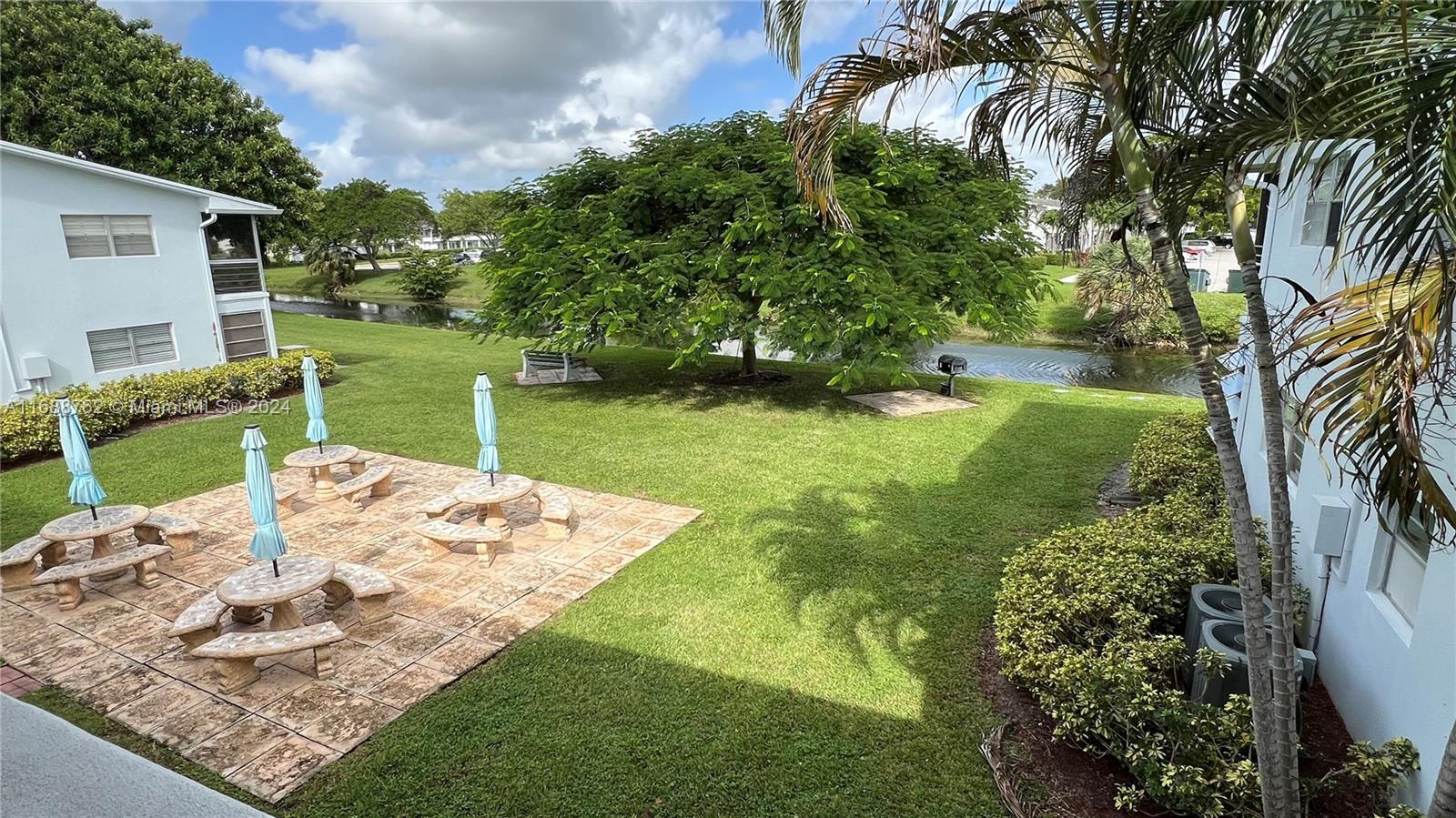 a view of a backyard with table and chairs potted plants and large tree