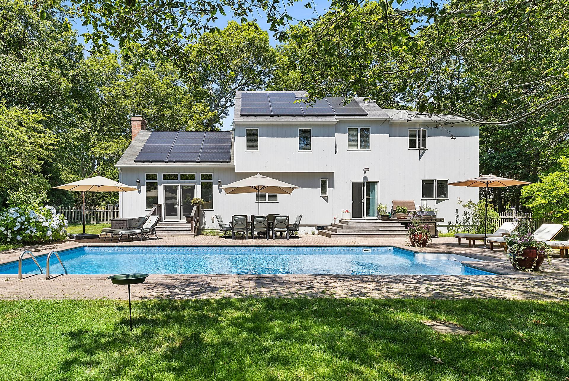 Back of house with solar panels, a yard, a fenced in pool, and a patio area