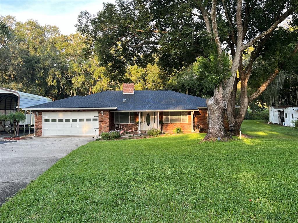 a view of a house with a yard and large trees