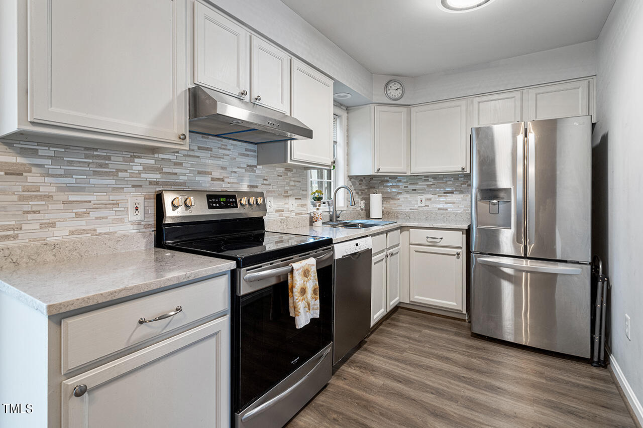 a kitchen with stainless steel appliances white cabinets and a refrigerator