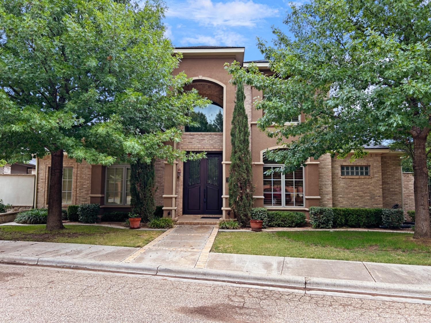 a front view of a house with a yard and trees