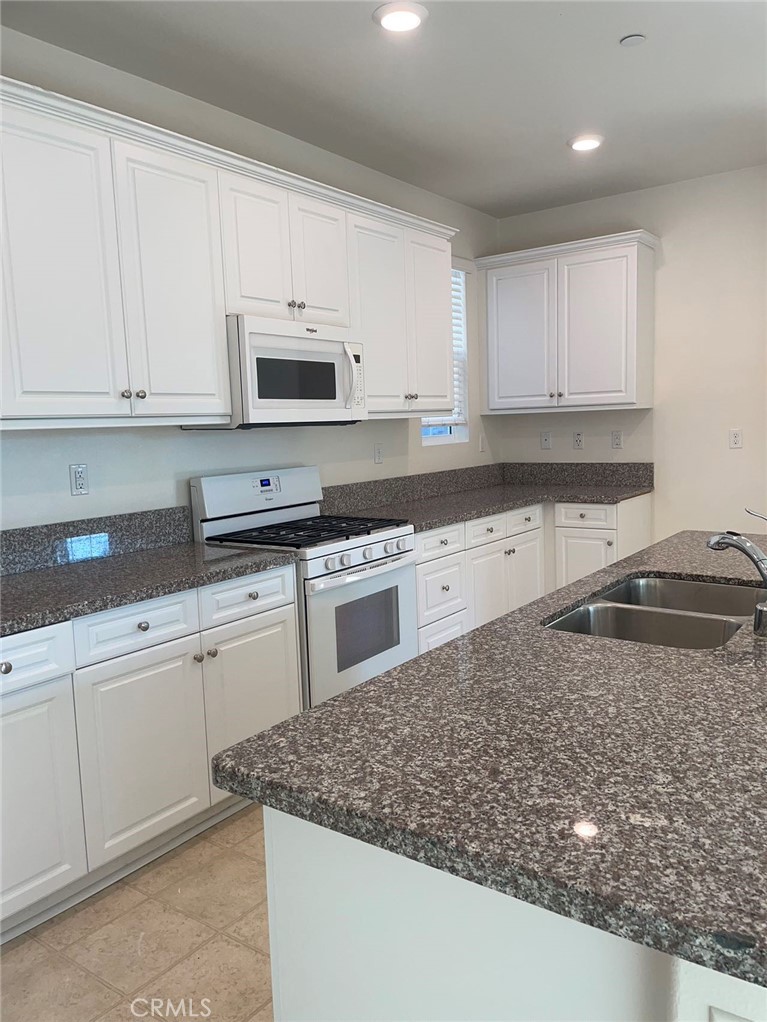 a kitchen with granite countertop white cabinets and stainless steel appliances