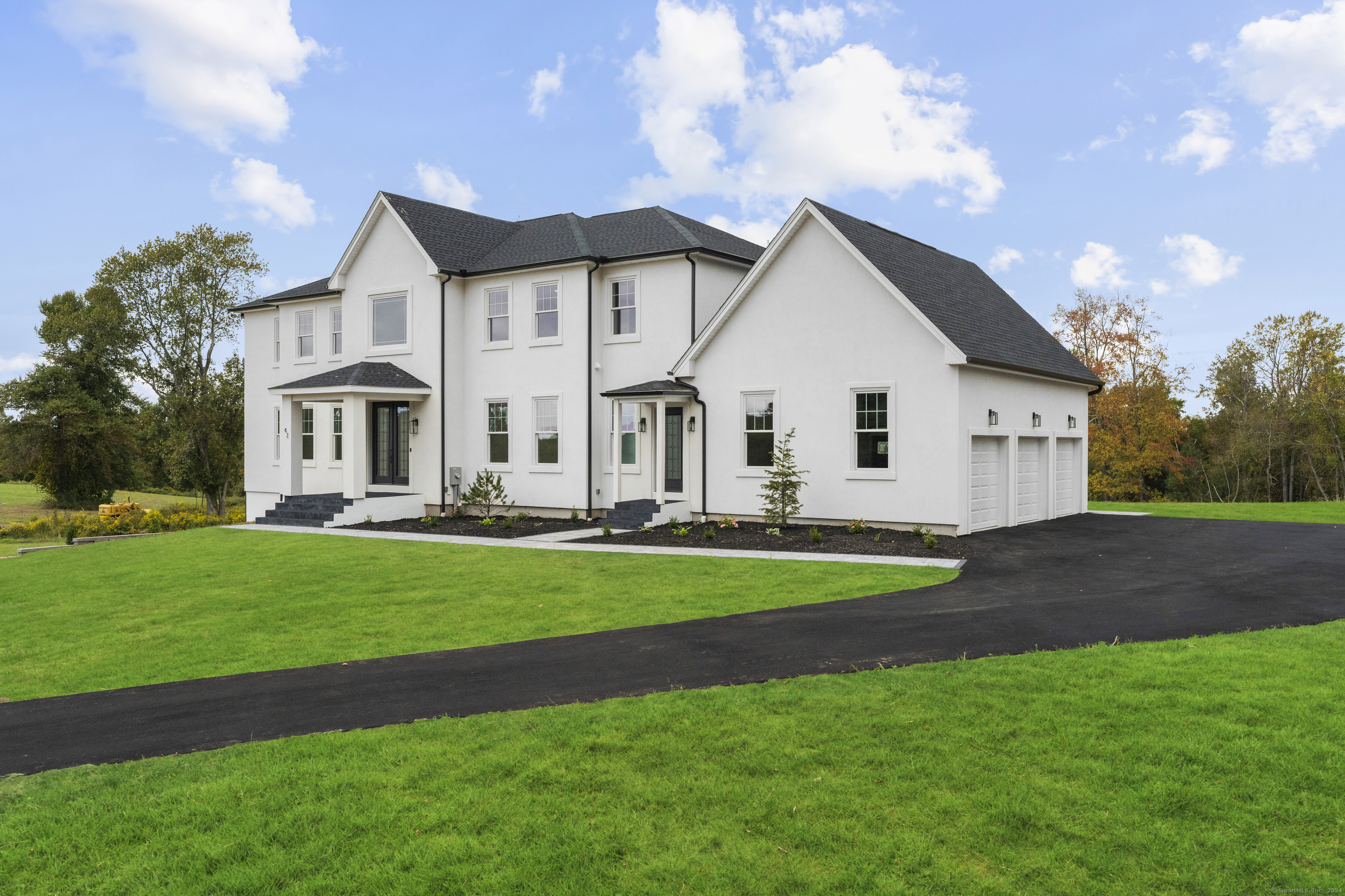 a view of a white house next to a yard with big trees