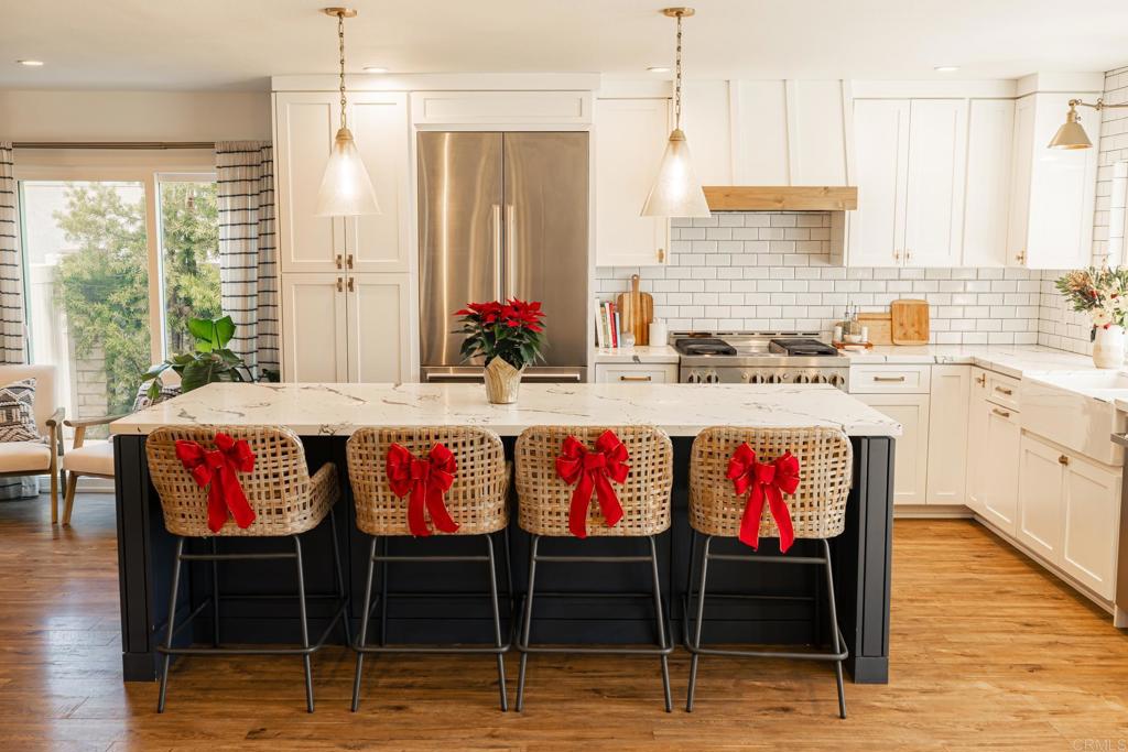 a kitchen with stainless steel appliances kitchen island granite countertop a dining table chairs and white cabinets