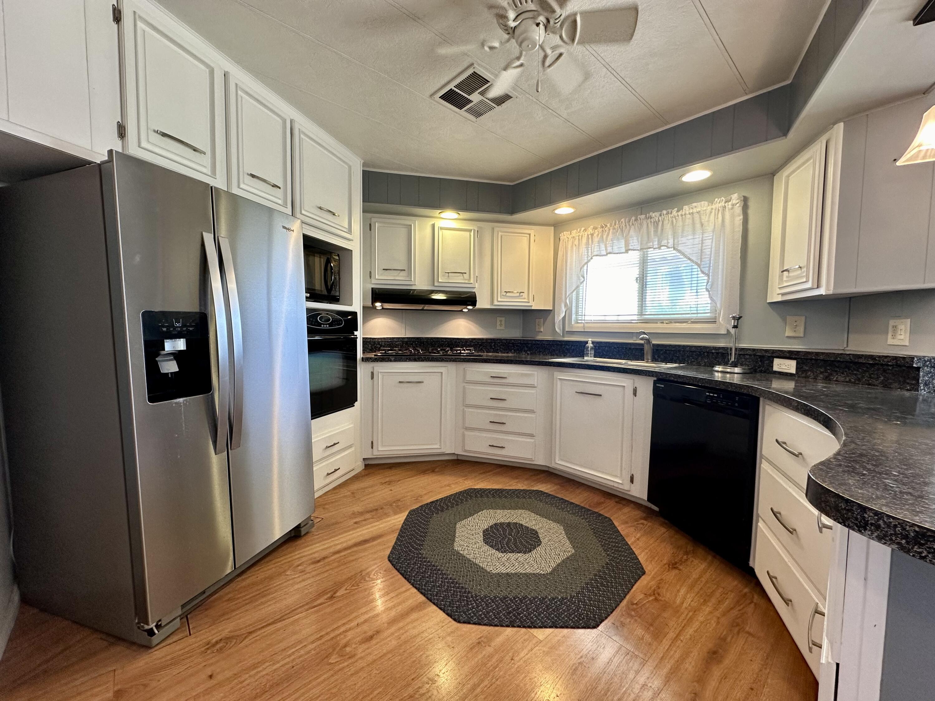 a kitchen with a sink a stove a refrigerator cabinets and wooden floor