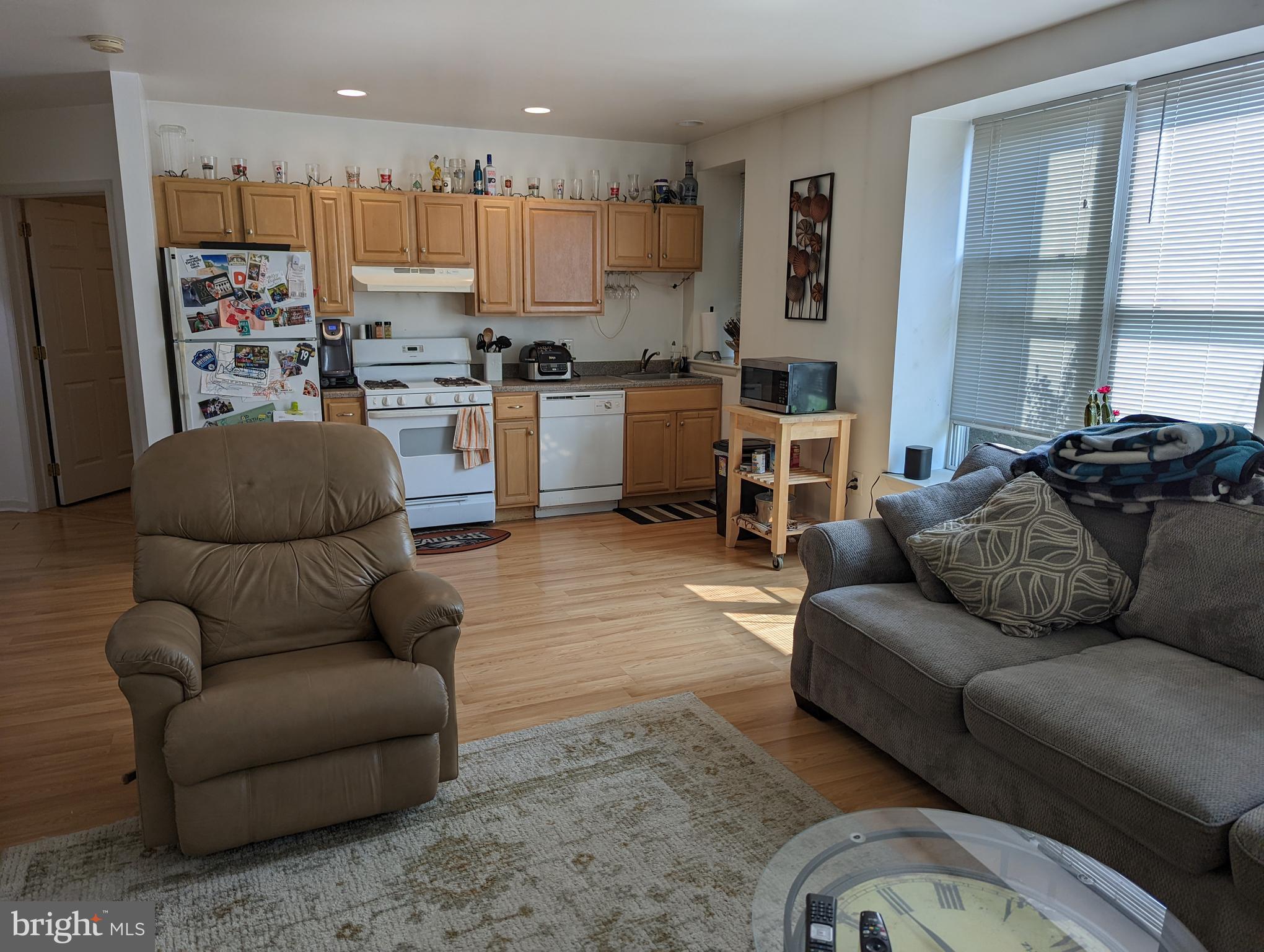 a living room with furniture kitchen area and a window