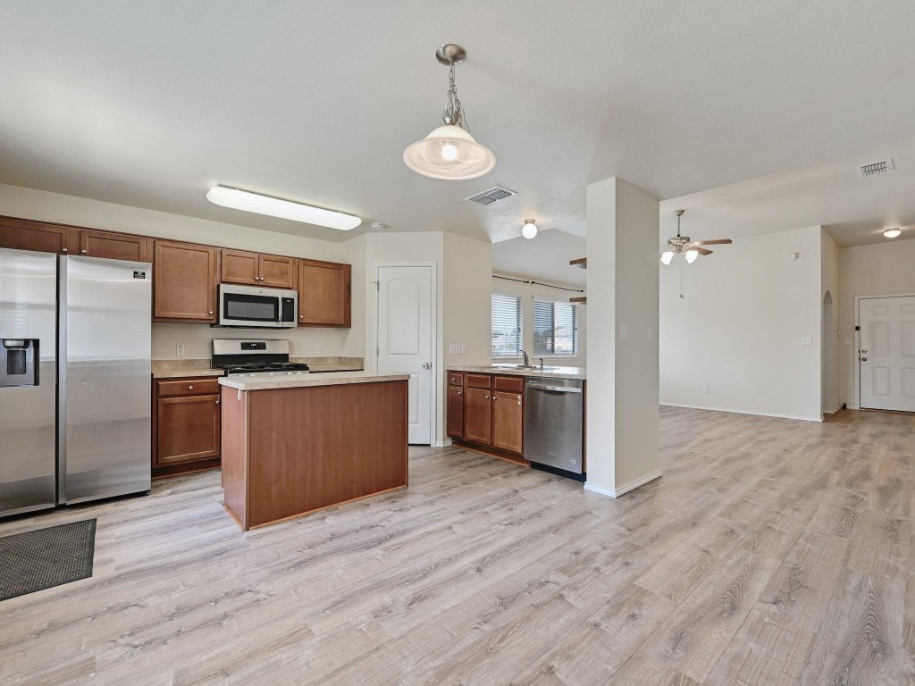 a large kitchen with stainless steel appliances kitchen island a large counter top and wooden floors