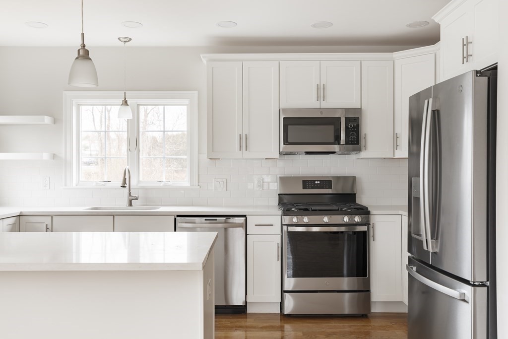 a kitchen with granite countertop a refrigerator stove and microwave